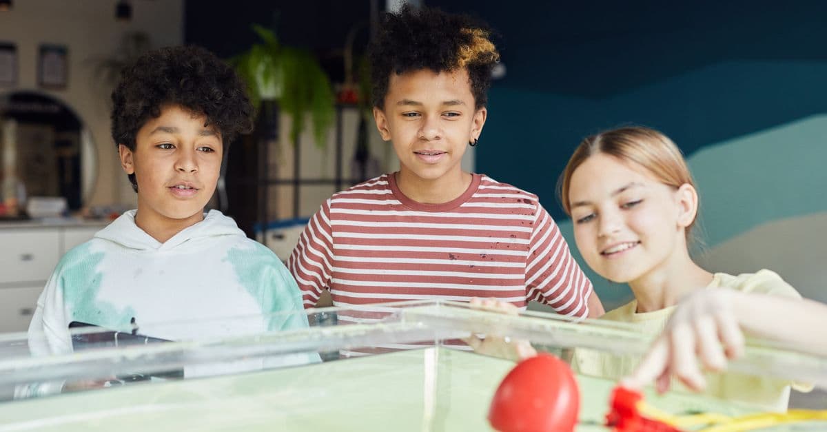 Group of smiling diverse children looking at new flying drone and examining it at workshop