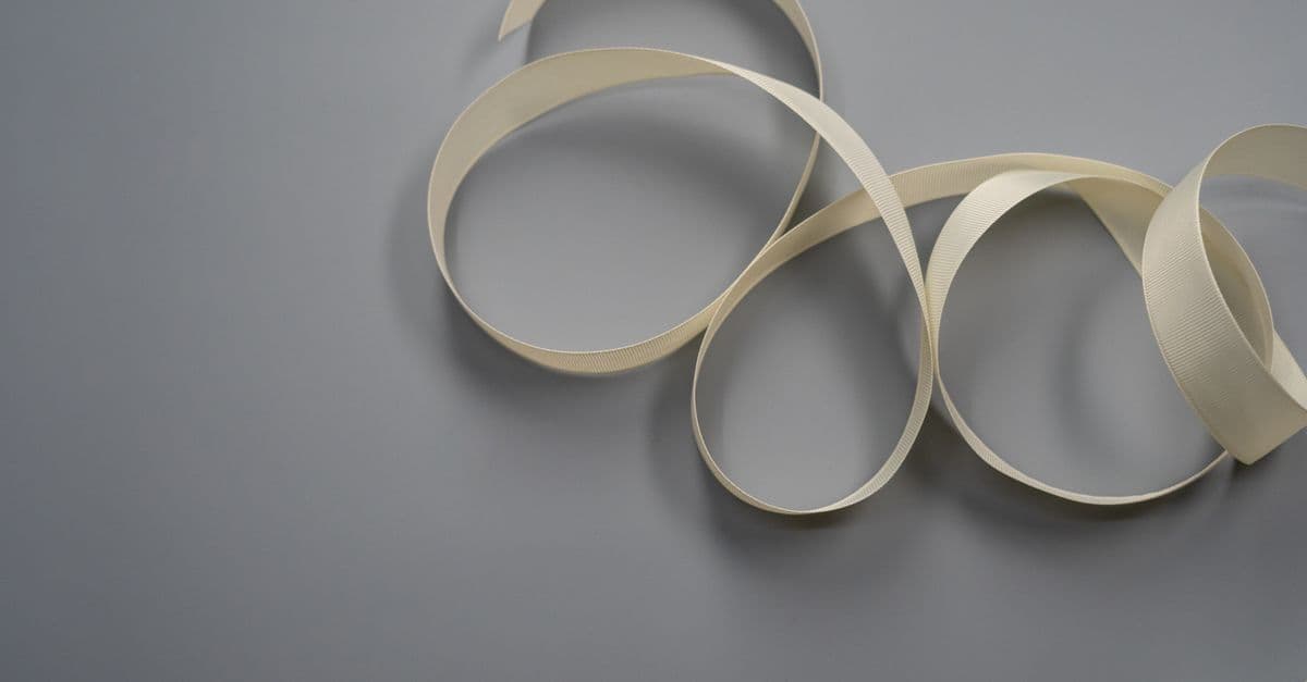A soft white ribbon elegantly arranged on a smooth grey surface, perfect for design projects.