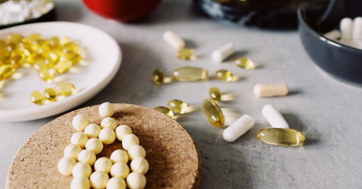 Close-up of assorted pills, capsules, and supplements on a marble surface, emphasizing healthcare and wellness.