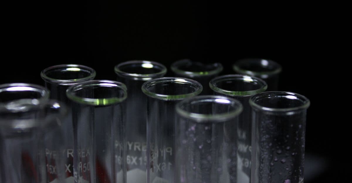 Glass test tubes with condensation in a dark lab environment.