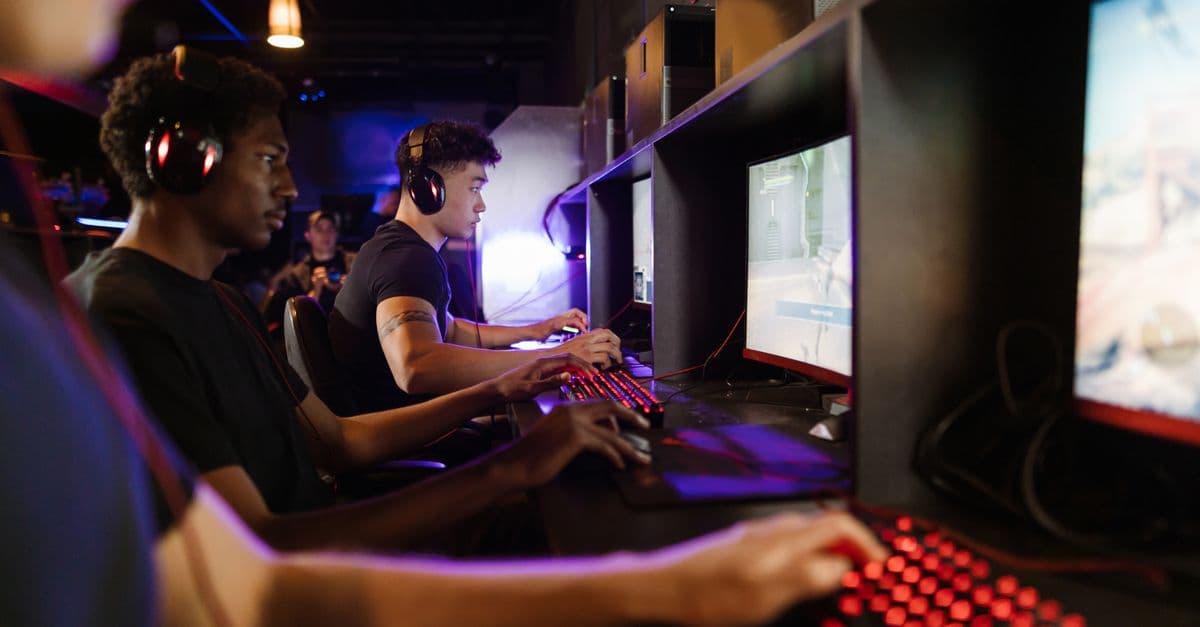 Young adults gaming at a modern LAN center with advanced PCs, showcasing intense gaming focus.