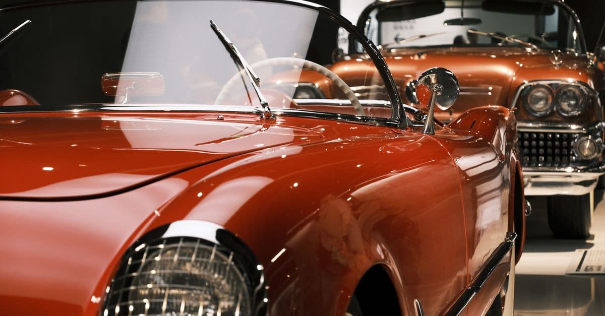 A beautifully preserved vintage red cabriolet showcased at a car exhibition indoors.