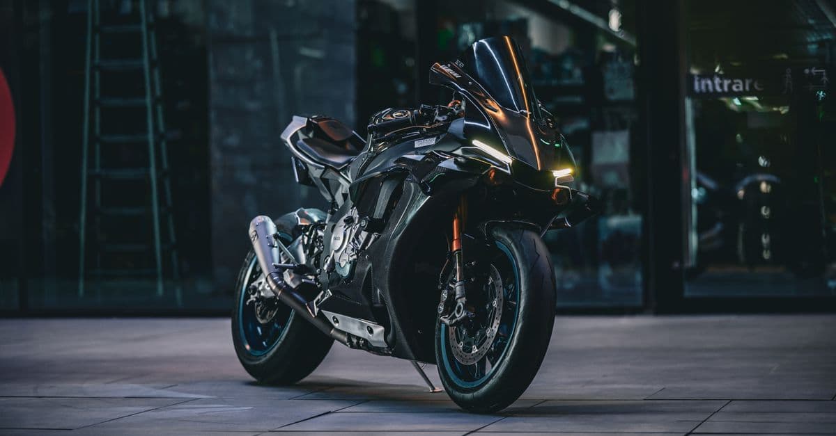 A modern black motorcycle parked in a dimly lit urban environment, showcasing its sleek design.