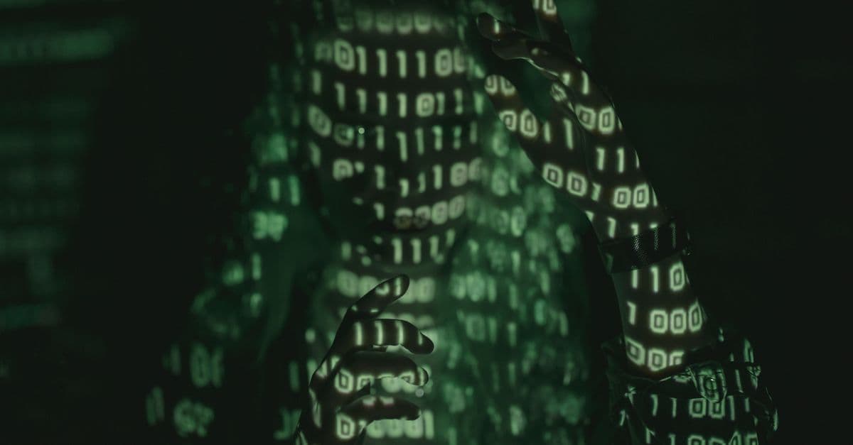 An unrecognizable person with binary code projected, symbolizing cybersecurity and digital coding.