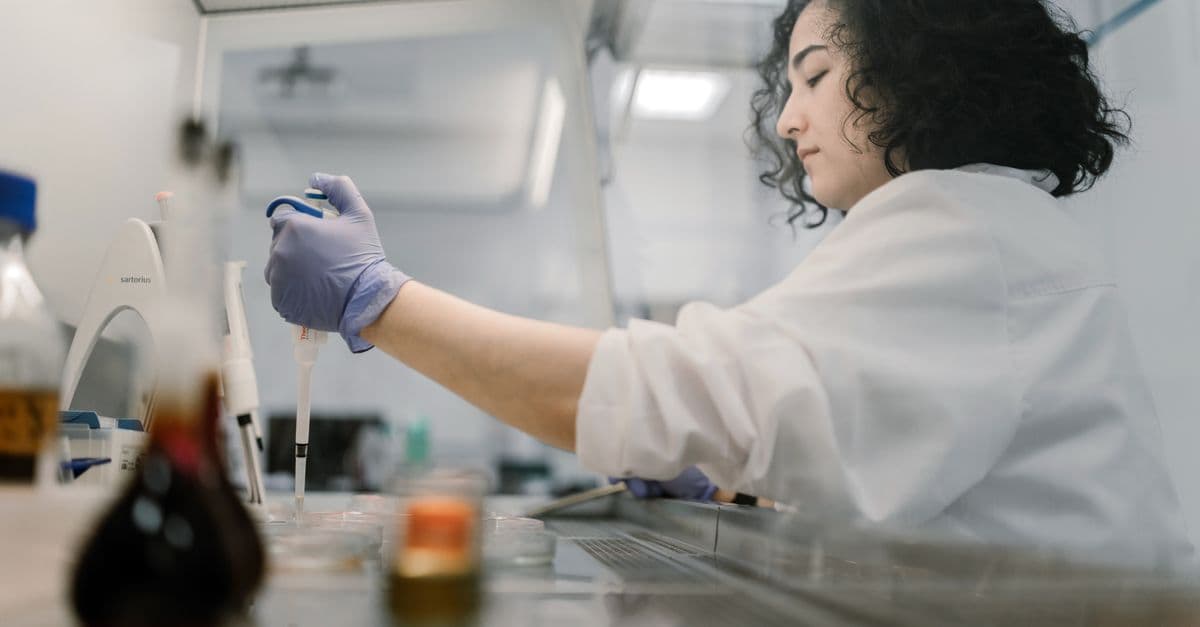 Woman in lab coat conducting research with pipette in modern laboratory.