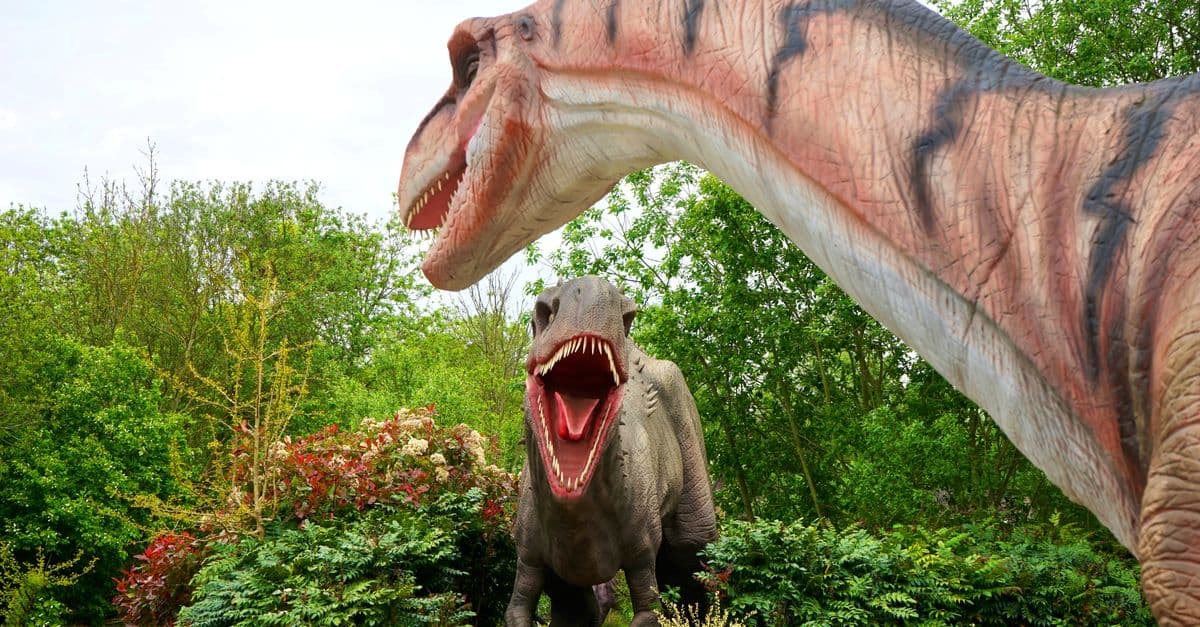 Realistic dinosaur sculptures in a lush park setting, evoking prehistoric times.
