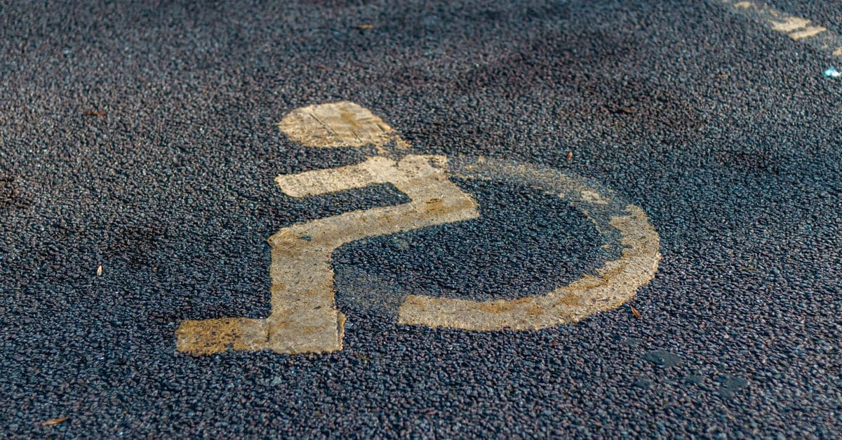 Close-up of a weathered handicap sign painted on a pavement, emphasizing accessibility.