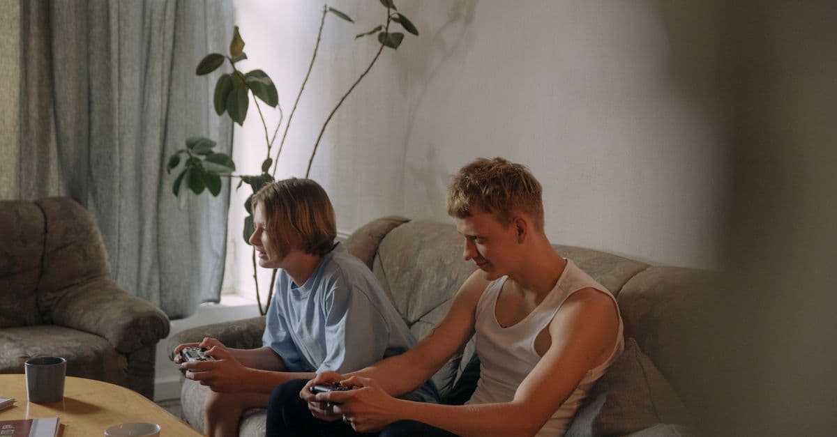 Two teenagers enjoying video games at home, immersed in their gaming session on a cozy couch.