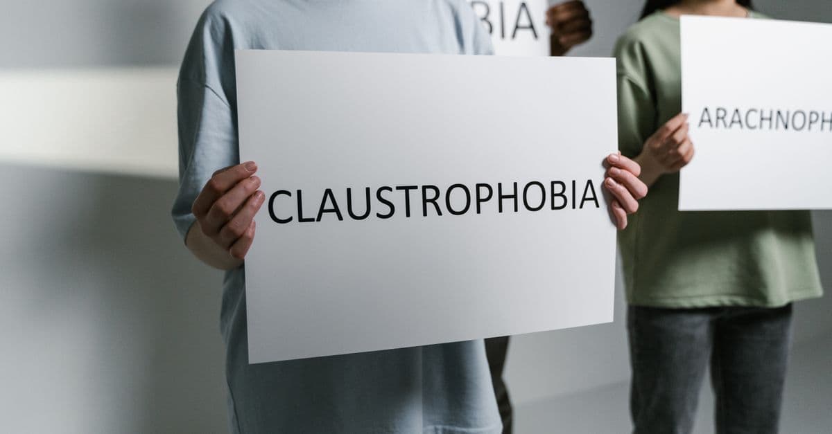 Group of individuals holding signs displaying phobia names in a neutral setting.