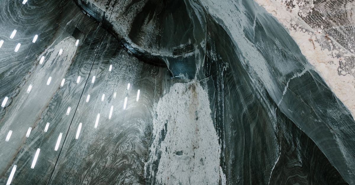 From above of hanging LED lamps and salty stalactites on uneven walls of Salina Turda mine in Romania