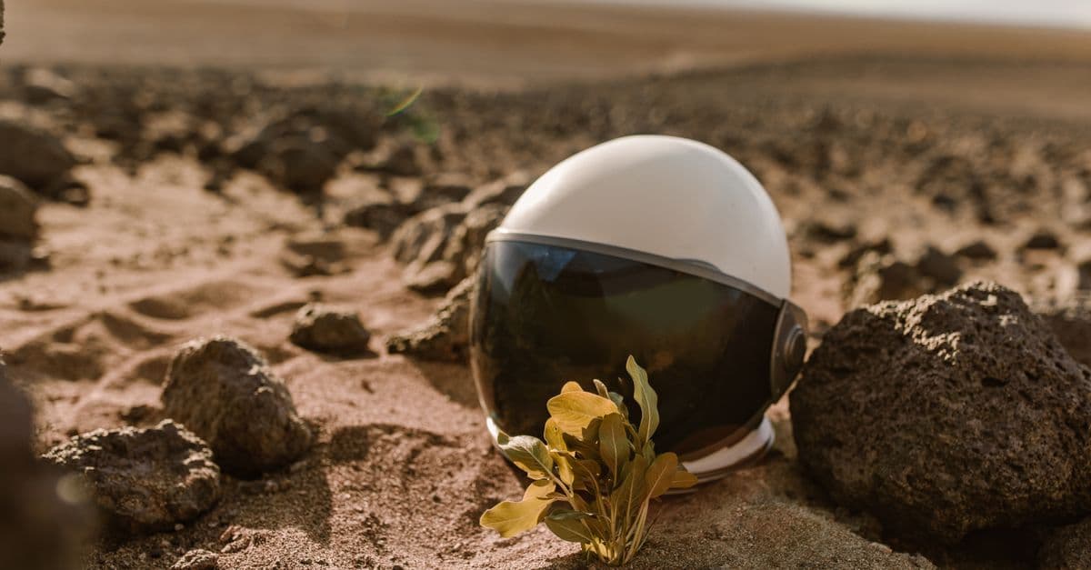 Close-up of an astronaut helmet on rocky desert terrain, evoking alien exploration.