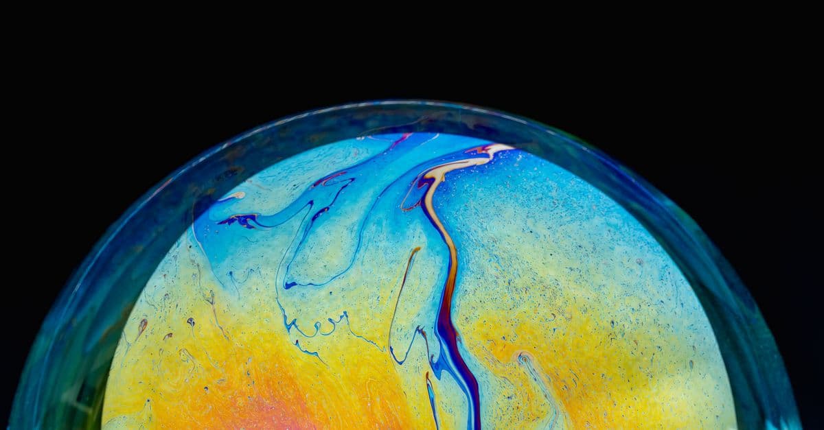 Close-up of a colorful iridescent soap bubble with a black background, showcasing vibrant patterns.