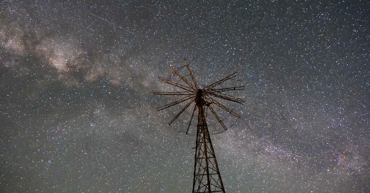Explore the night sky with a silhouette of a windmill under the Milky Way in Witjira, Australia.