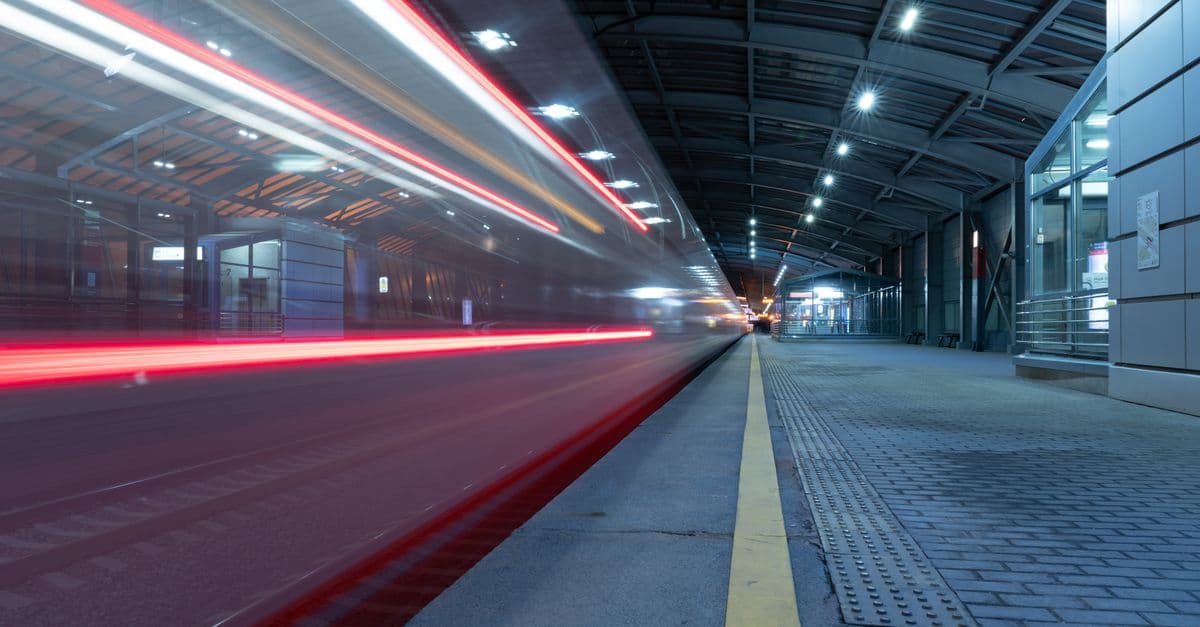 A scenic view of a train station at night with striking motion blur lighting effects.