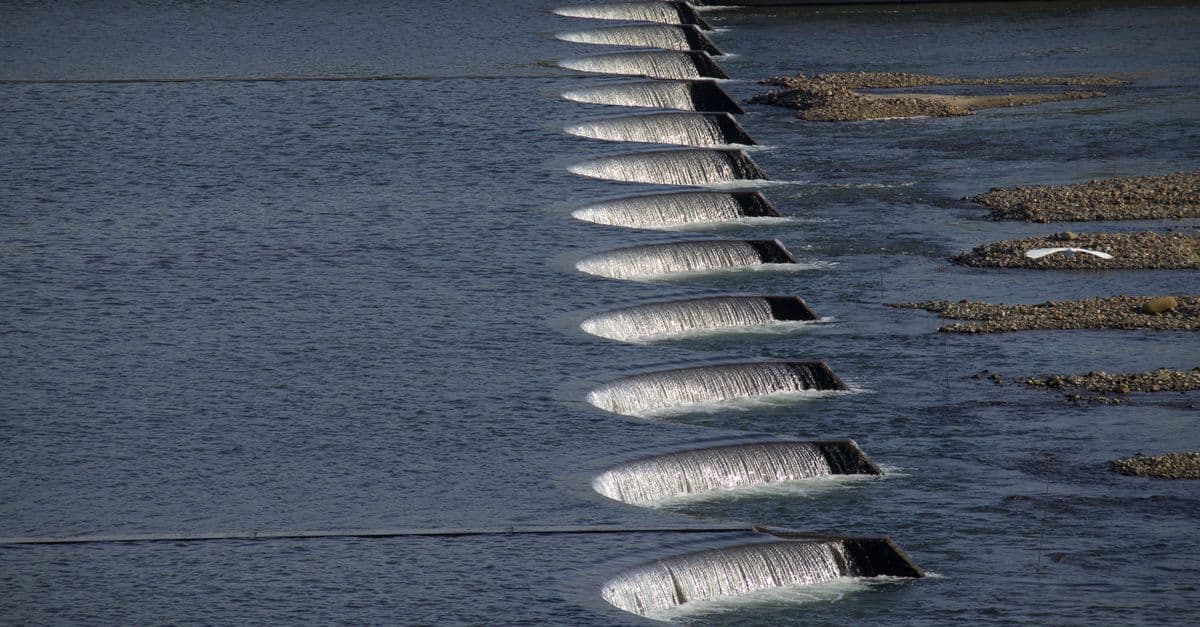 A series of cascading waterfalls over dam structures, showcasing flowing water and stone formations.