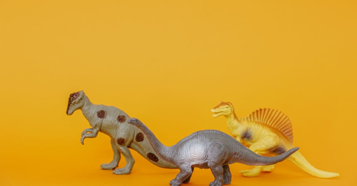 Three dinosaur toy figurines on a vibrant yellow background, ideal for playful concepts.