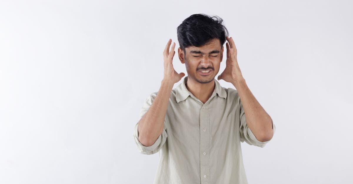Young man expressing frustration, hands on head, isolated background.
