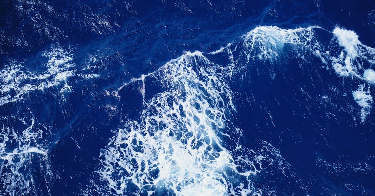 Aerial view of vibrant ocean waves crashing with dynamic white foam.