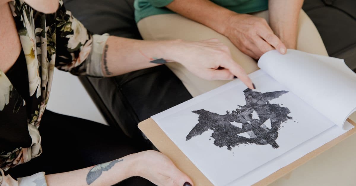 Two adults discuss a Rorschach inkblot test, focusing on interpretation and analysis.