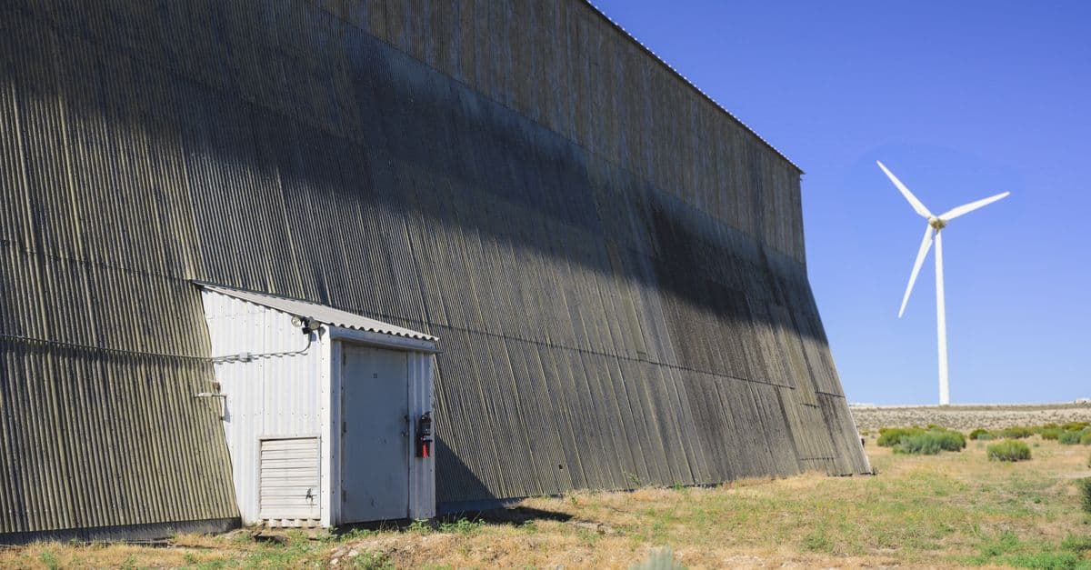 A wind turbine stands next to an industrial building in Boise, demonstrating renewable energy.