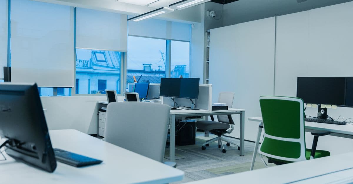 Bright and modern office environment with computer workstations and large windows.