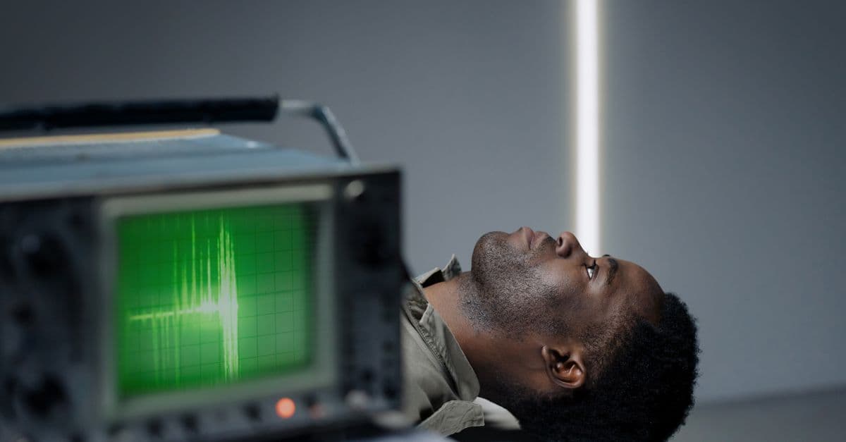 Black man lying in a studio beside an oscillograph screen, conceptually captured.