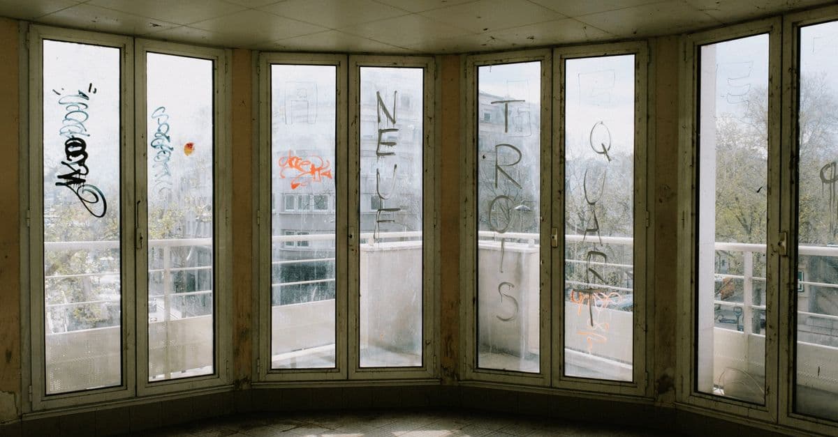 Abandoned building interior with graffiti on windows in an urban setting.