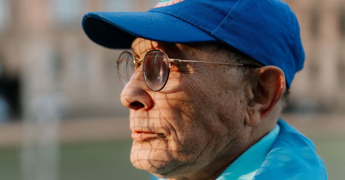 Portrait of a senior man with eyeglasses in a blue cap, enjoying outdoors.