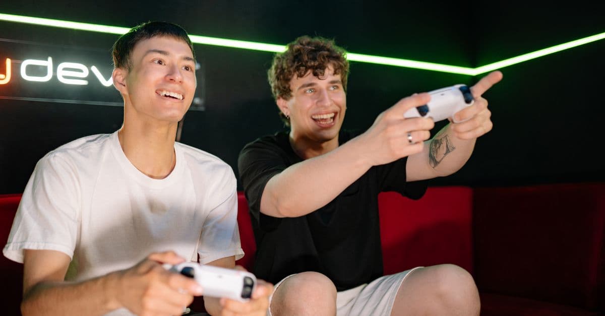 Two young men playing video games indoors, having fun and engaging with controllers.