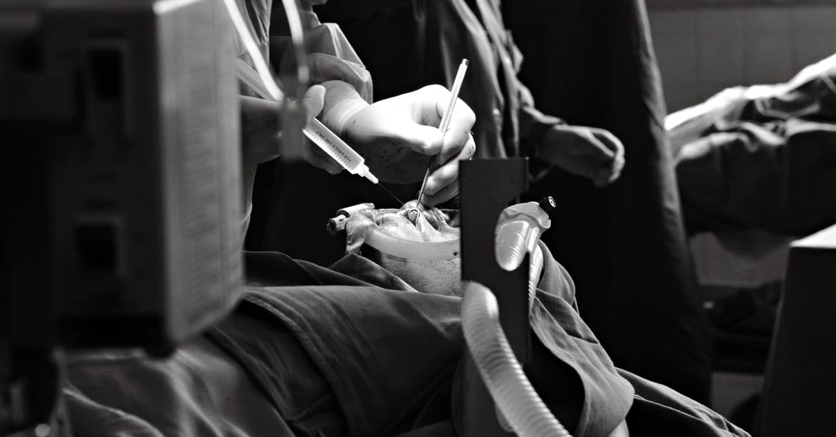 Monochrome photo capturing a surgical operation with detailed focus on the hands and instruments.