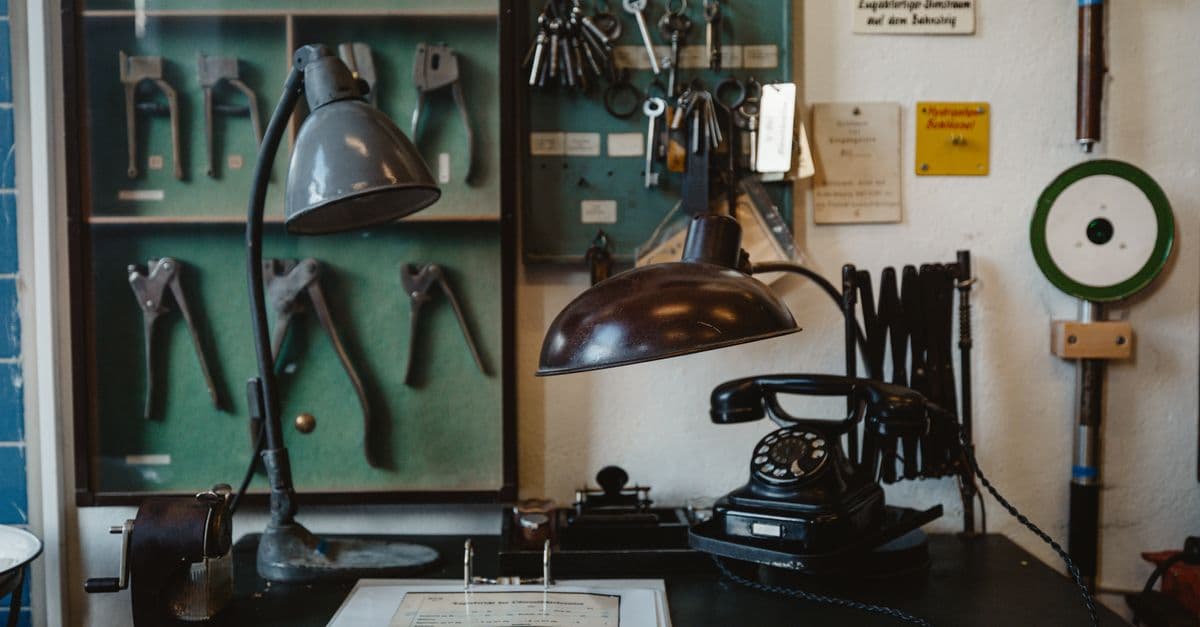A nostalgic vintage workshop desk featuring classic tools, an old lamp, and a rotary phone, evoking a bygone era.