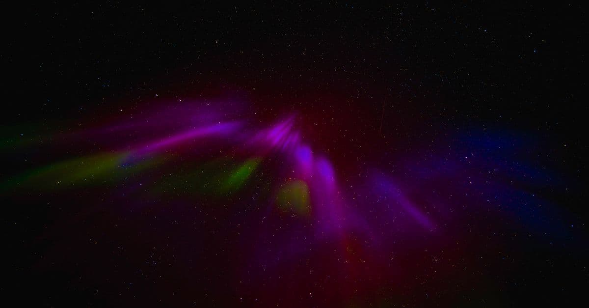 Vibrant aurora borealis illuminates the starry night sky over Norway.