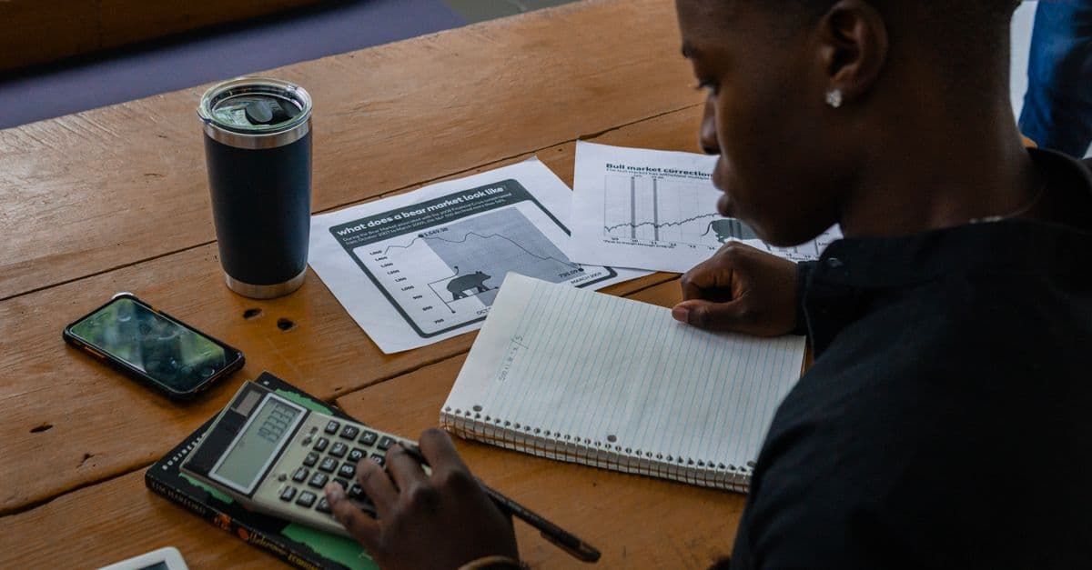 Young professional evaluating financial data using a calculator and notes.