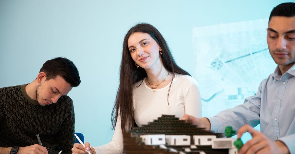 Three people collaborating on an architectural model in an office setting, emphasizing teamwork.