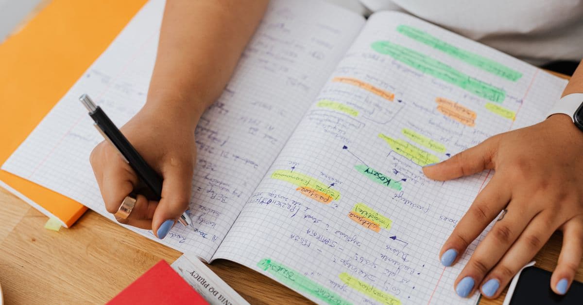 A person writing and highlighting notes in a graph notebook. Ideal for education and productivity themes.