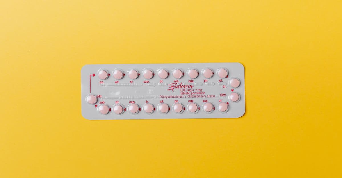 Close-up of a blister pack of pink pills on a vivid yellow background for medication concept.