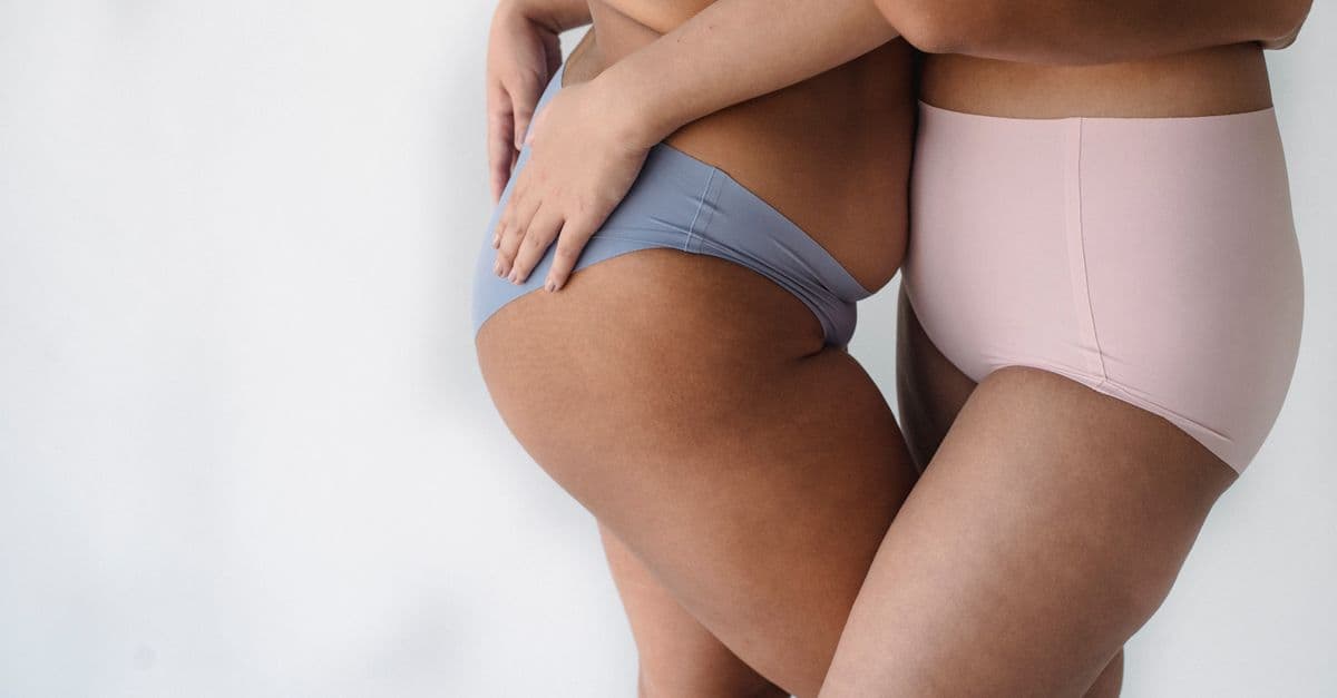 Two women in underwear embrace, celebrating body positivity and diversity.