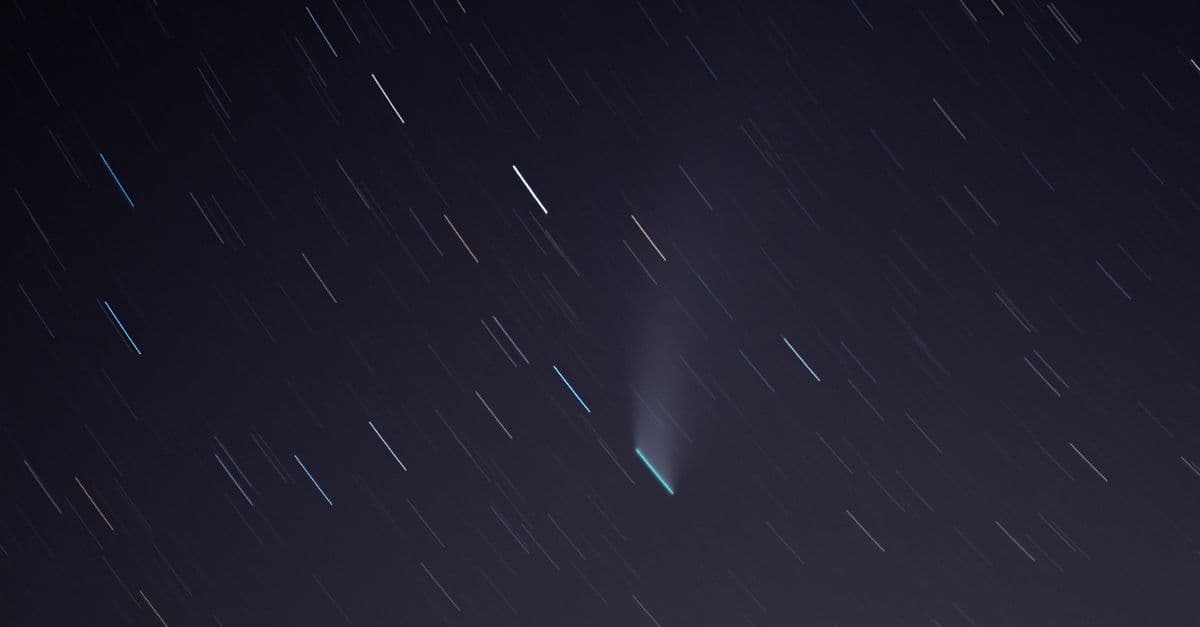 Long exposure of star trails and a comet illuminating the night sky over Airolo, Switzerland.