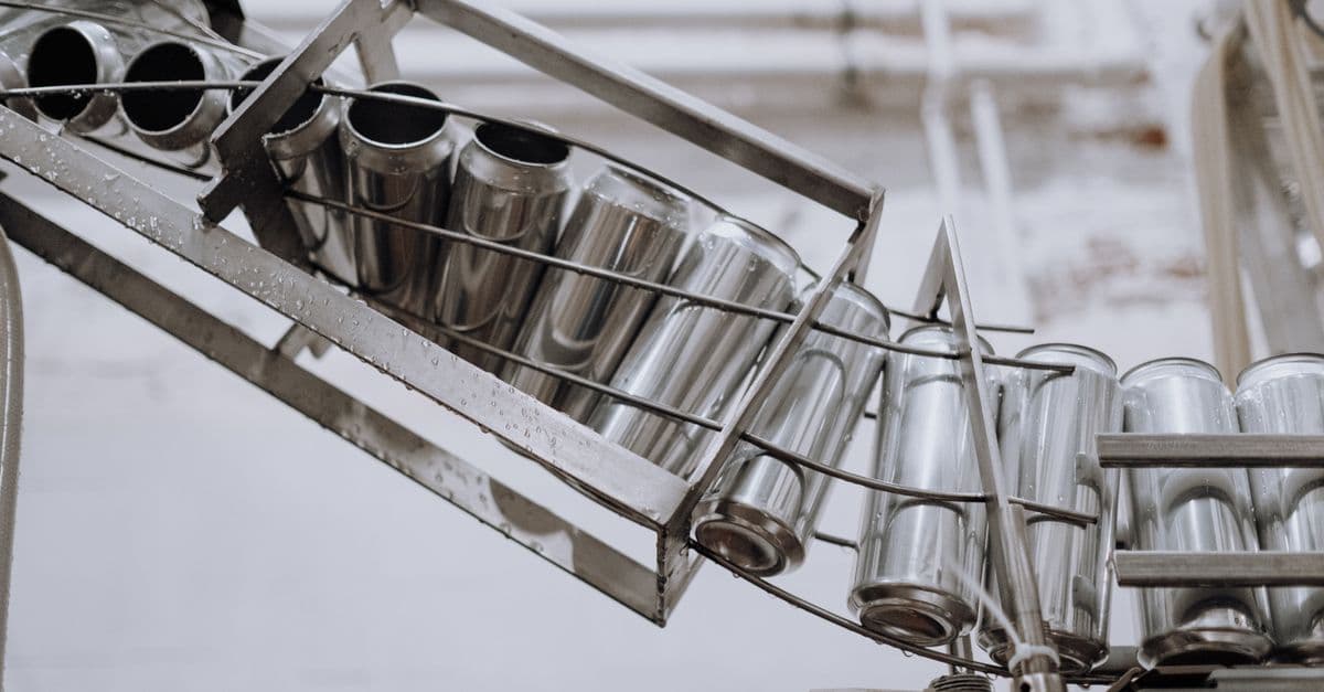 Conveyor belt with empty aluminum cans in a factory setting, showcasing production equipment.