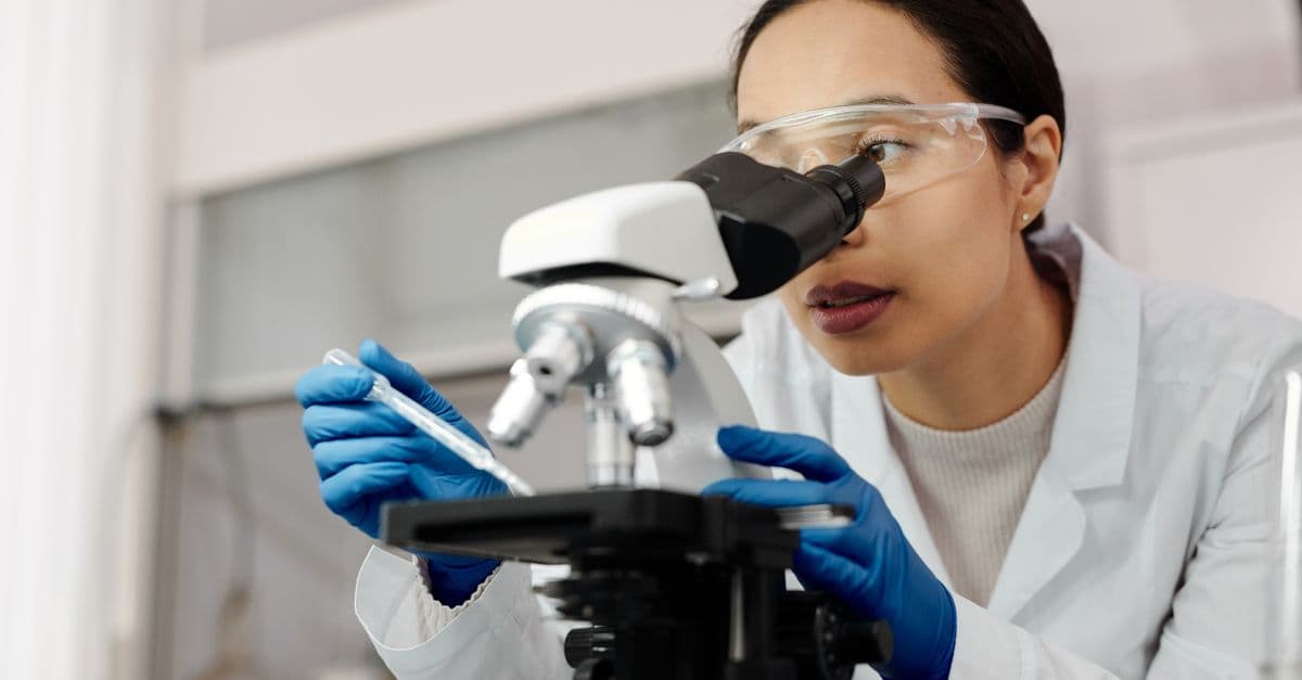 A female scientist examines samples using a microscope in a laboratory setting.