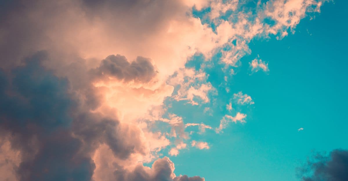 Captivating image of dramatic clouds against a vibrant blue sky with warm sunset tones.