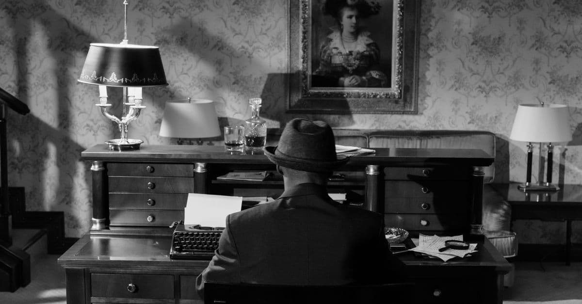 A vintage monochrome scene featuring a detective in a fedora hat at a typewriter, evoking classic noir mystery.
