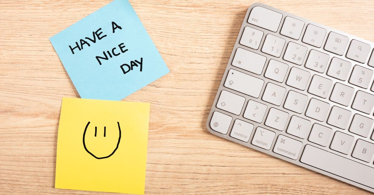 A cheerful desk setup with a note saying 'Have a Nice Day' next to a keyboard.