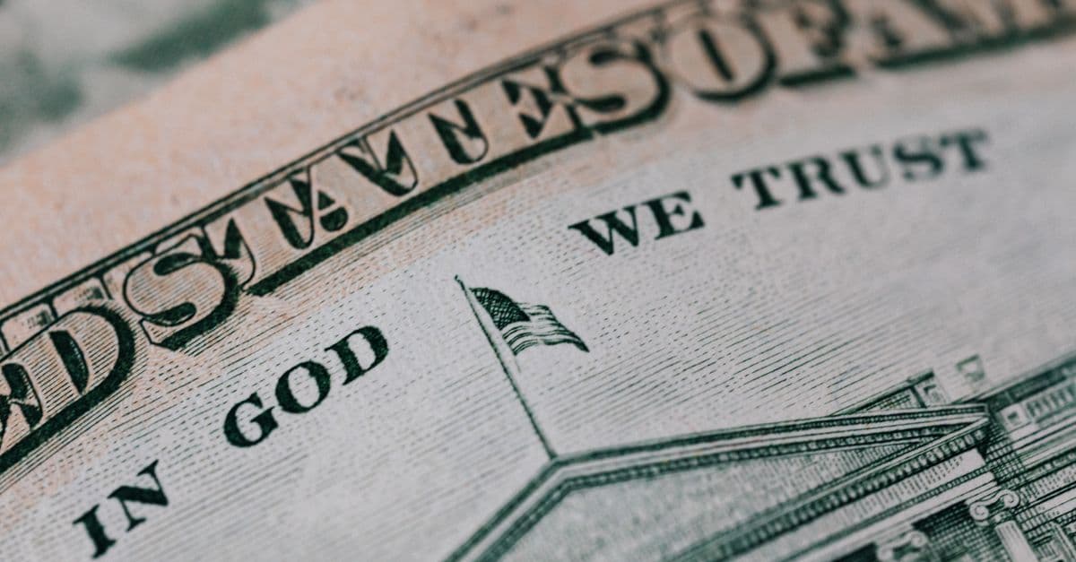 Closeup of ten dollar with inscription In God We Trust bill placed on table with different money