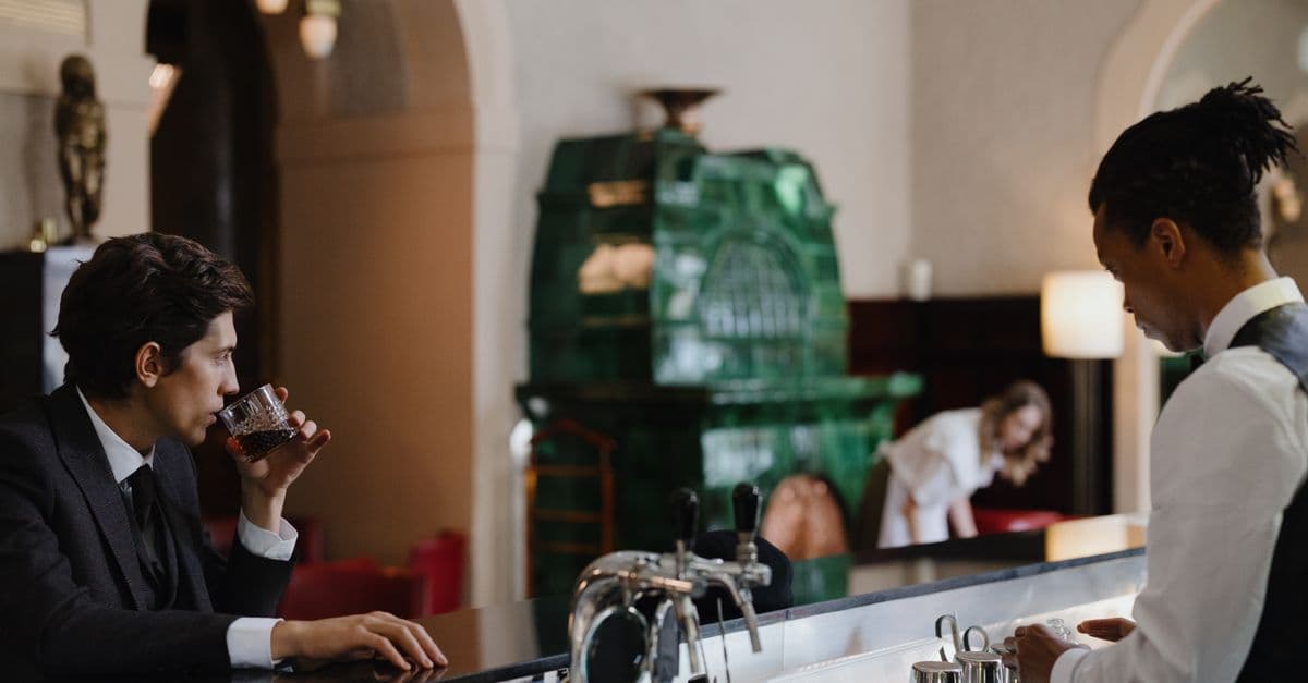 An intimate bar scene featuring a customer enjoying whisky and a bartender at work.