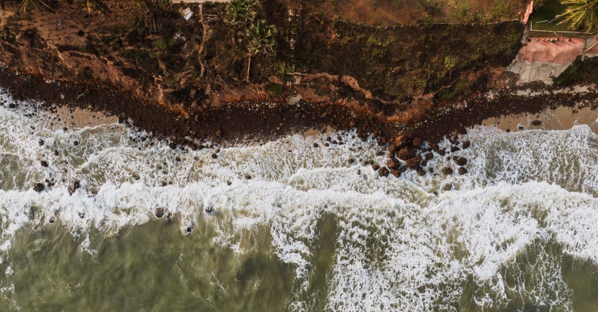 Drone shot capturing a dramatic view of ocean waves hitting a rocky coastline.