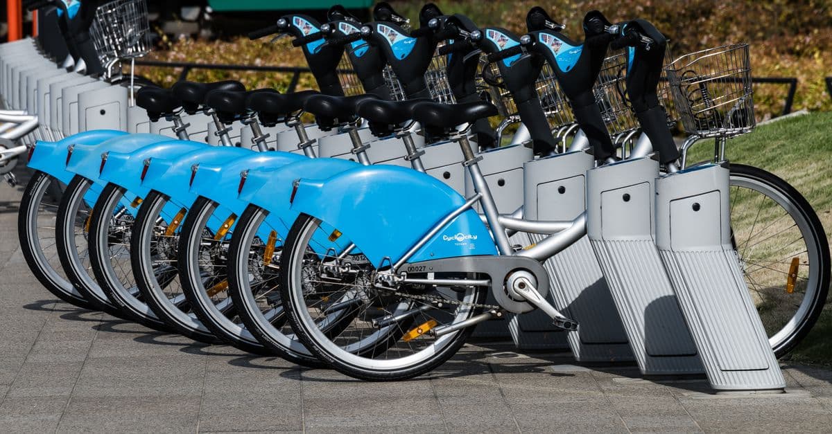 A row of blue rental bicycles parked in an urban area of Toyama City, Japan.