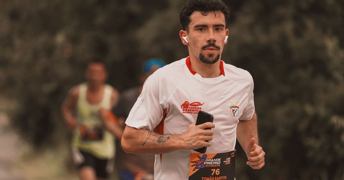 Focused male runner in race jersey with earbuds during outdoor marathon.