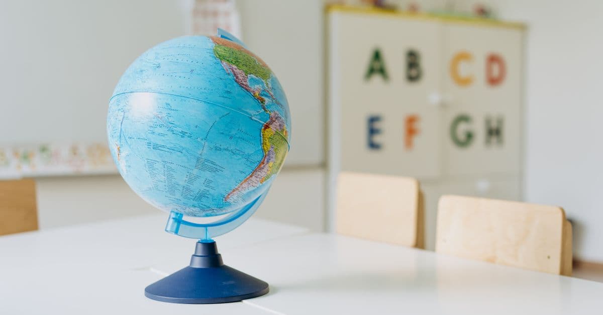 A vibrant globe sits on a table in a classroom, ideal for educational themes.