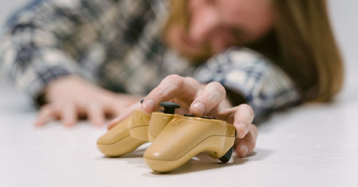 Hand reaching out to touch a yellow game controller, focus on interaction.